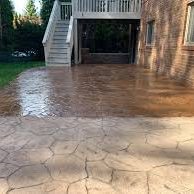 Driveway with a fresh coat of sealant applied to protect it. The surface has a glossy, reflective finish that enhances the appearance and provides a protective layer. The sealant has been evenly spread across the entire driveway, giving it a smooth, well-maintained look.