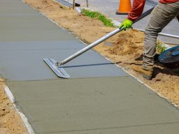 Ready Set Concrete worker smoothing out freshly laid concrete for a neighborhood sidewalk