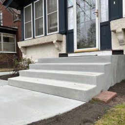 A new 4 step concrete staircase leading up to a homes front door entry