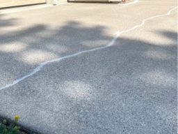 Concrete surface with previously cracked areas that have been filled with caulk. The caulked sections show a smooth, even finish where the cracks were repaired. The surrounding concrete is clean and free of damage, highlighting the contrast between the repaired and original areas