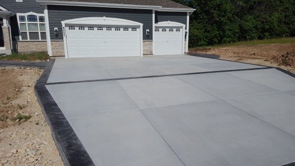 Newly installed modern concrete driveway with a dark concrete rim 